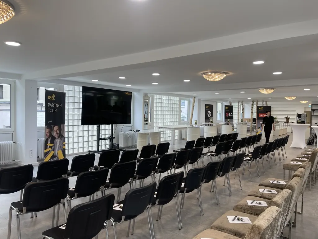 Tagung mit Stuhlreihen und großem TV-Screen in der Eventlocation Die Glockenstraße